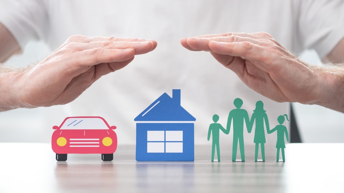 Hands sheltering models of a car, house and family